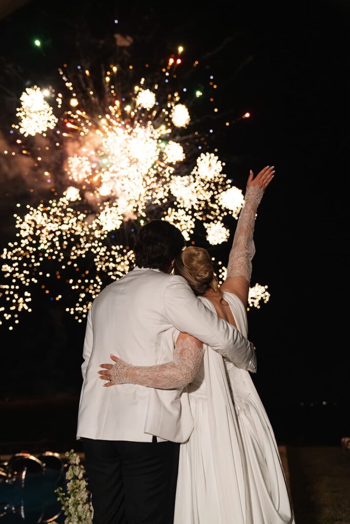 Brautpaar Sophie und Erik umarmen sich bei Nacht vor einem leuchtenden Feuerwerk während ihrer Hochzeit in der Toskana.