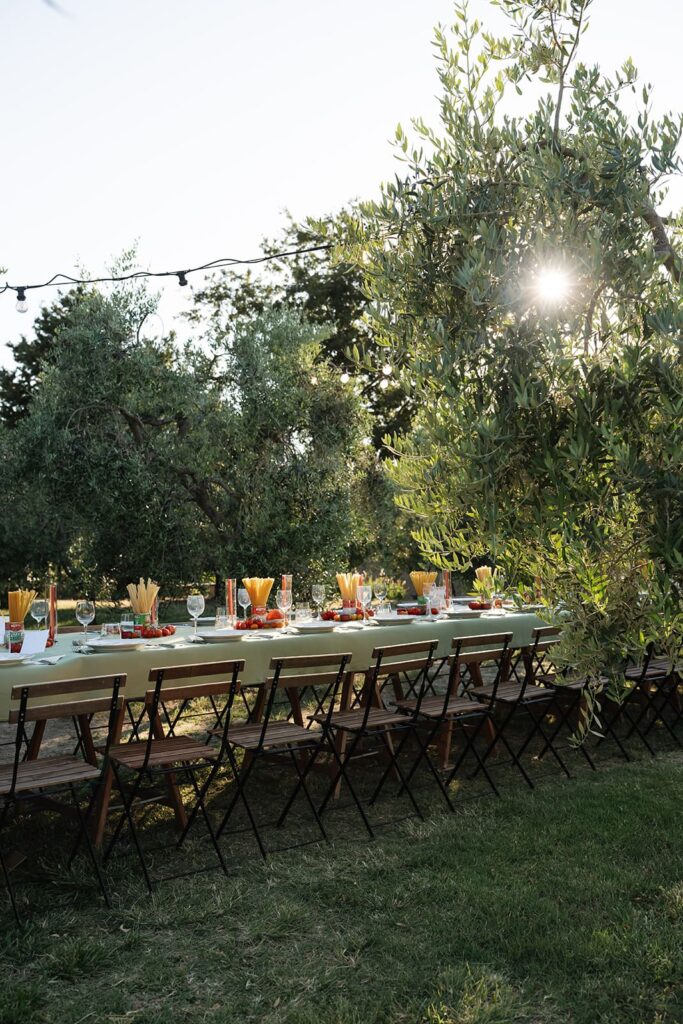 Aufnahme einer langen gedeckten Tafel zwischen Olivenbäumen bei einer italienischen Hochzeitsfeier in Volterra.