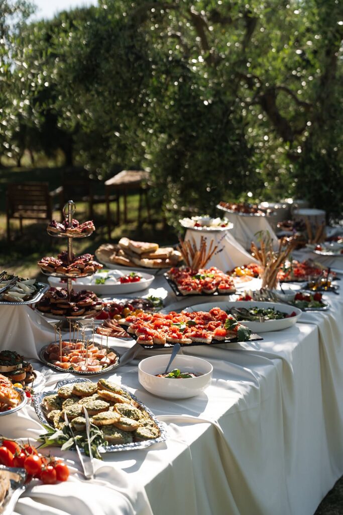 Reichhaltiges italienisches Buffet mit Antipasti und verschiedenen Speisen im Garten einer Hochzeitslocation in der Toskana.