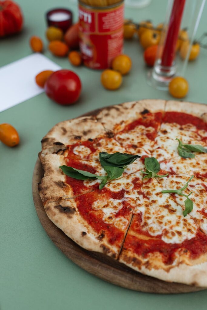 Frisch gebackene italienische Pizza Margherita mit Tomaten, Mozzarella und Basilikum auf einer gedeckten Tafel.