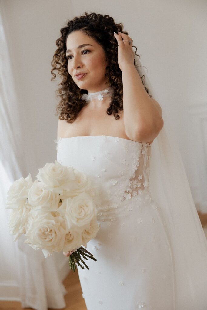 Braut Sali im eleganten weißen Hochzeitskleid mit Schleier und einem üppigen Brautstrauß aus weißen Rosen.