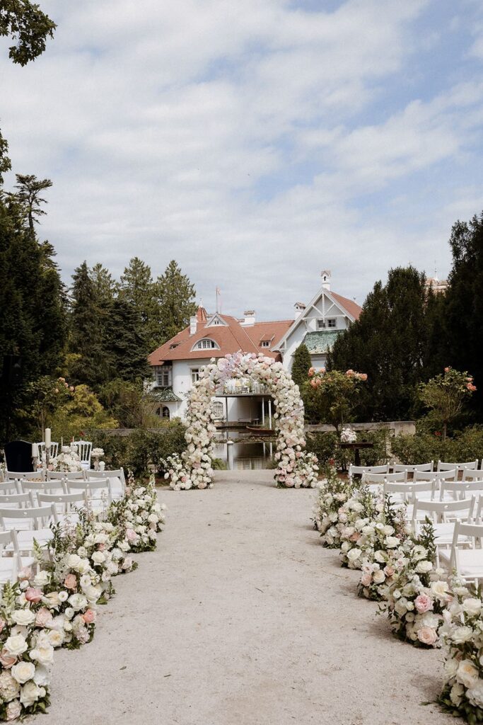 Opulenter Blumenbogen aus weißen, cremefarbenen und zartrosa Blüten als romantische Hochzeitsdekoration im Schloss Schönau.