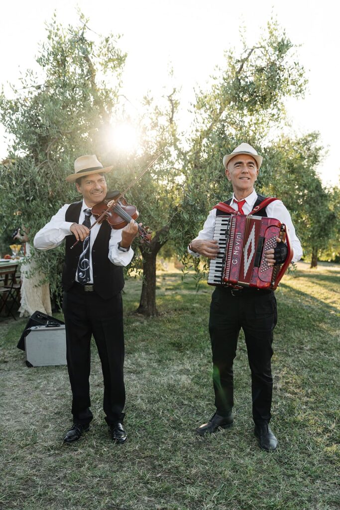 Zwei italienische Livemusiker mit Akkordeon und Gesang bei einer Pizza-Party im Olivenhain in der Toskana