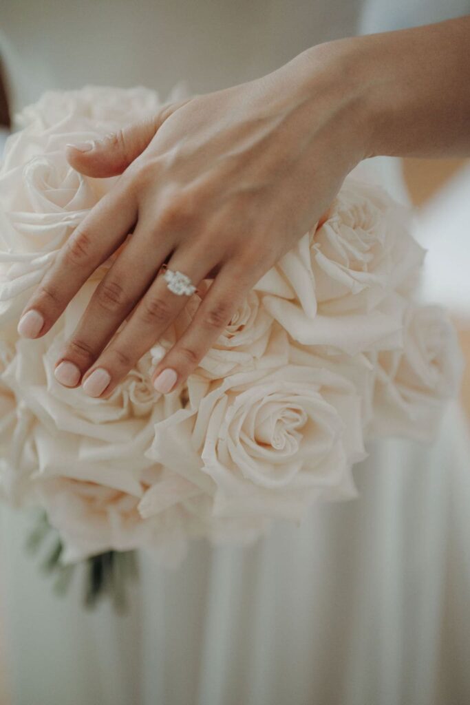 Nahaufnahme eines eleganten Brautstraußes aus cremefarbenen Rosen, gehalten von der Braut.