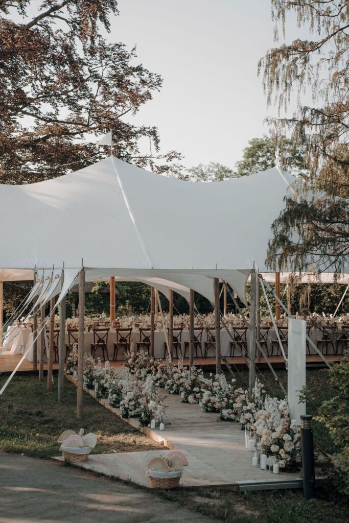 Großzügiges weißes Hochzeitsfestzelt im Grünen mit eleganter Gestaltung und floraler Dekoration.